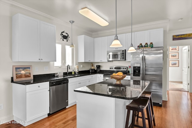 kitchen featuring appliances with stainless steel finishes, white cabinetry, a kitchen island, and sink