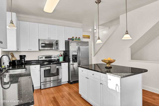 kitchen featuring appliances with stainless steel finishes, dark stone counters, sink, white cabinets, and a center island