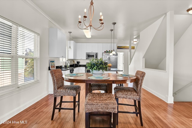 dining space featuring sink, light hardwood / wood-style flooring, a healthy amount of sunlight, and a notable chandelier