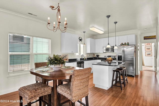 kitchen with white cabinets, pendant lighting, a kitchen island, and stainless steel appliances