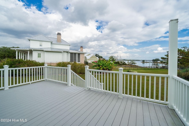 wooden terrace with a water view and a yard