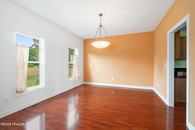 unfurnished room with dark hardwood / wood-style flooring and a wealth of natural light