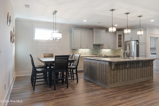 kitchen featuring dark hardwood / wood-style flooring, stainless steel fridge with ice dispenser, a kitchen breakfast bar, and a kitchen island with sink