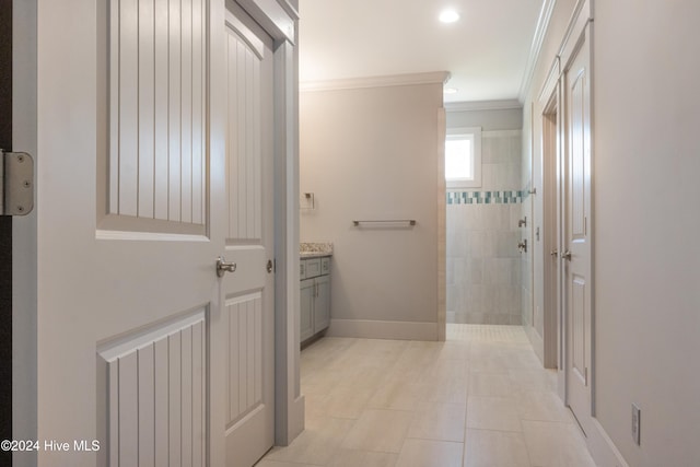 bathroom with a tile shower, crown molding, tile patterned flooring, and vanity