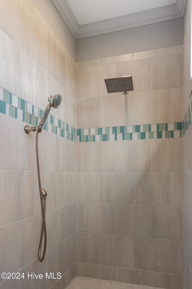 bathroom featuring ornamental molding and tiled shower