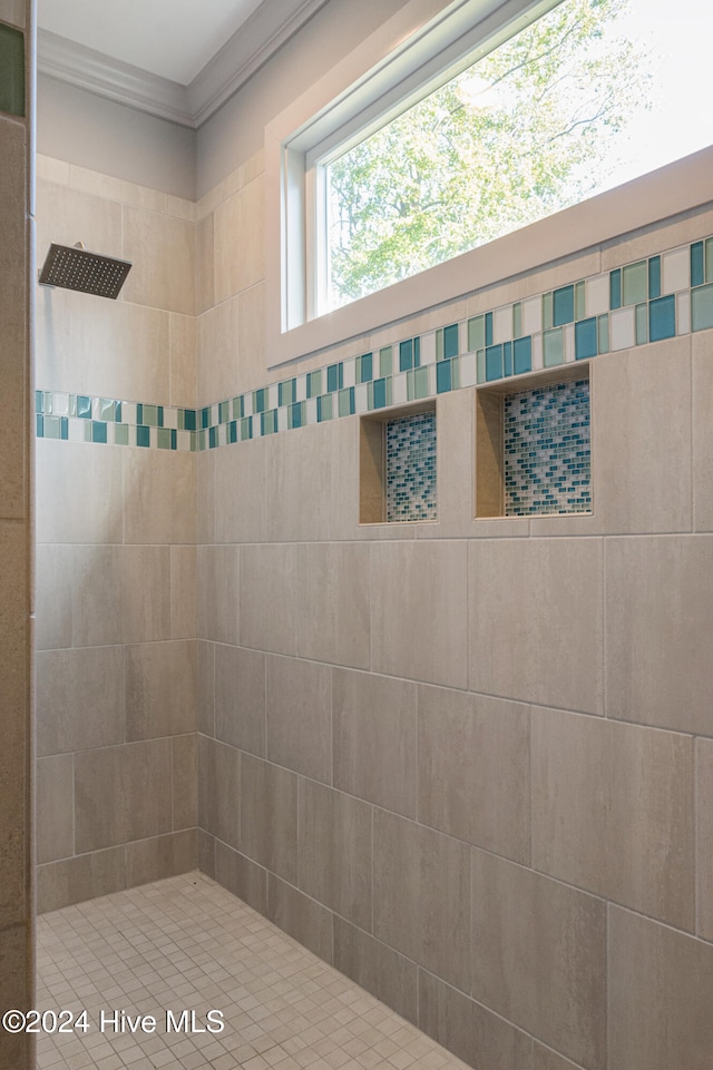 bathroom with tiled shower and crown molding