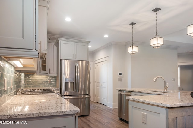 kitchen with light stone countertops, wood-type flooring, stainless steel appliances, sink, and decorative light fixtures