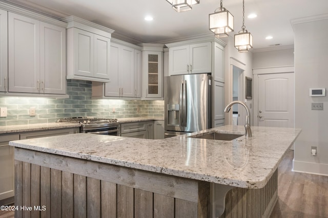 kitchen with a large island with sink, appliances with stainless steel finishes, sink, a kitchen bar, and pendant lighting