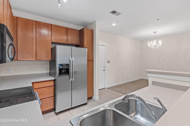 kitchen featuring stainless steel fridge, sink, an inviting chandelier, range, and hanging light fixtures