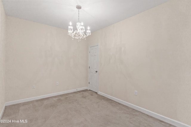 carpeted spare room featuring a notable chandelier