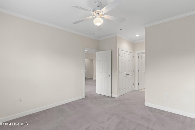 unfurnished bedroom with ceiling fan, light colored carpet, and crown molding