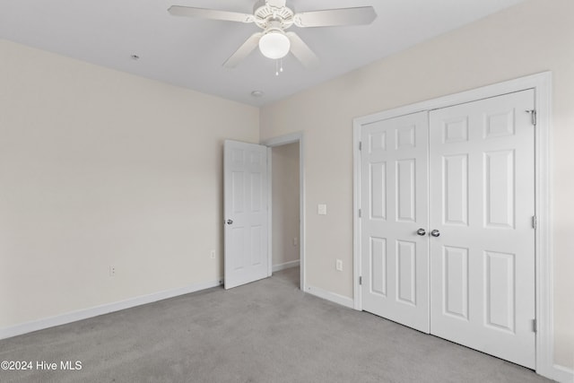 unfurnished bedroom with light carpet, a closet, and ceiling fan