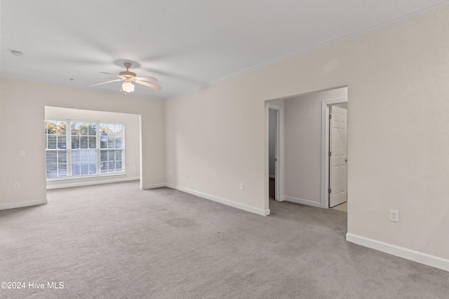 empty room with ceiling fan, light colored carpet, and ornamental molding