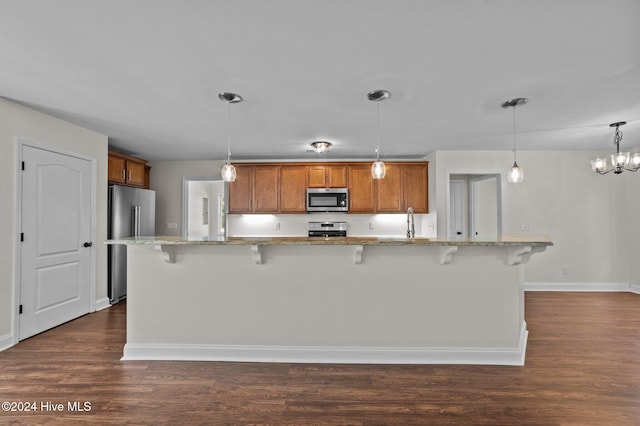 kitchen featuring appliances with stainless steel finishes, a breakfast bar area, hanging light fixtures, and dark hardwood / wood-style flooring