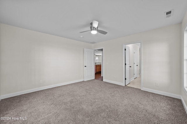 unfurnished bedroom with connected bathroom, light carpet, and ceiling fan