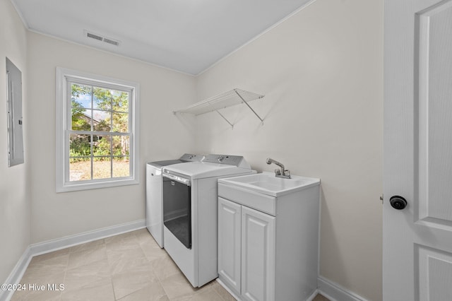 clothes washing area with sink, electric panel, washer and clothes dryer, and cabinets