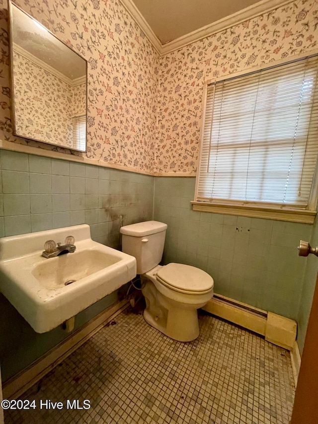 bathroom featuring toilet, tile patterned flooring, baseboard heating, crown molding, and tile walls