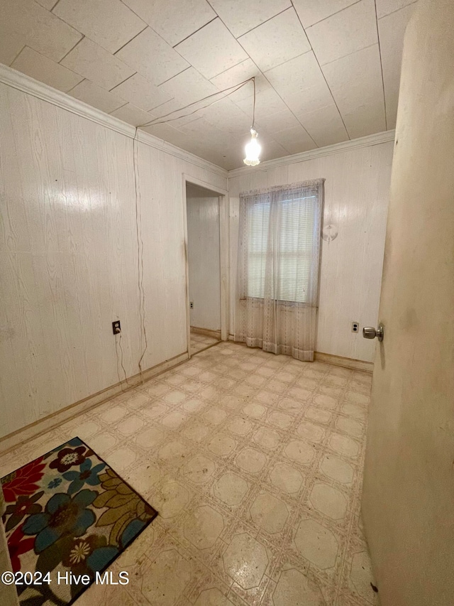 spare room with crown molding and wood walls