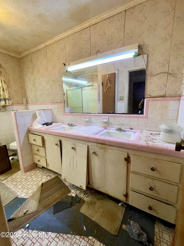 bathroom with vanity, ornamental molding, toilet, and tile walls