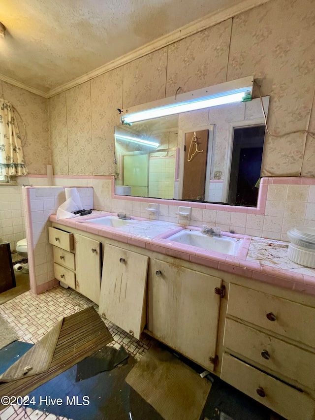 bathroom featuring vanity, toilet, crown molding, and tile walls