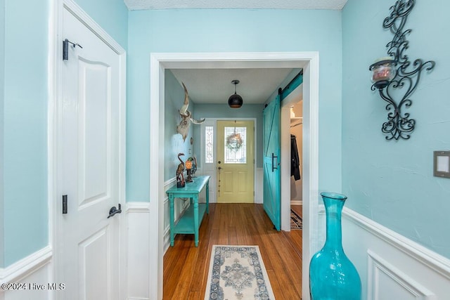 corridor featuring wood finished floors and a barn door