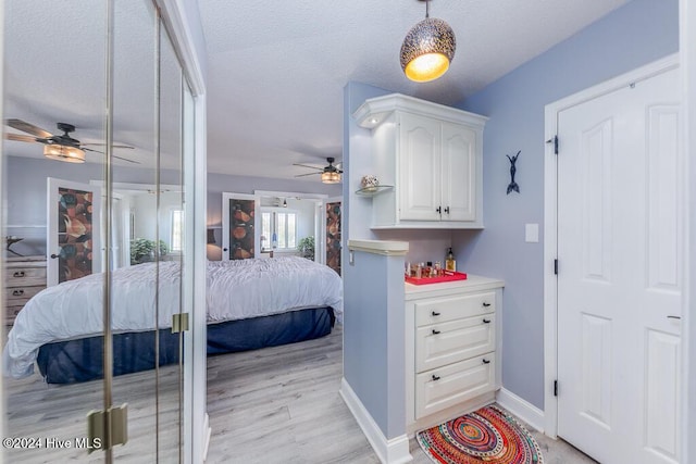 bedroom with baseboards, light wood-style flooring, and a textured ceiling