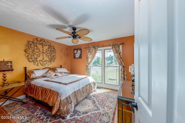 bedroom with access to exterior, ceiling fan, a textured ceiling, and wood finished floors