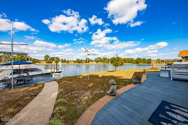 dock area featuring a water view, boat lift, and a yard