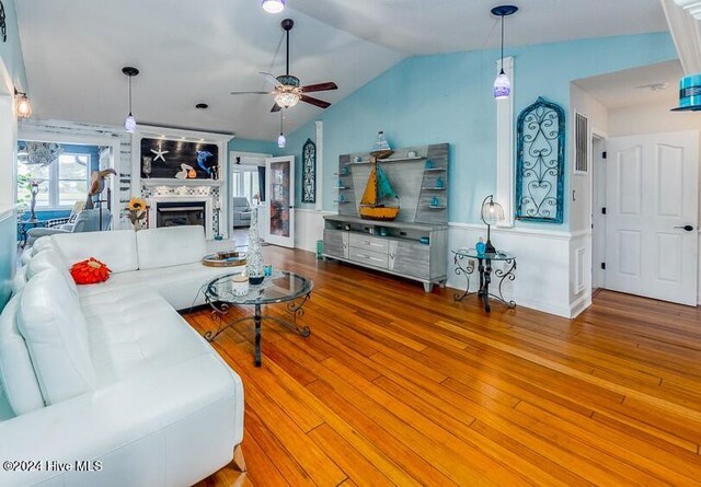 living room with lofted ceiling, a ceiling fan, wood finished floors, and a tile fireplace