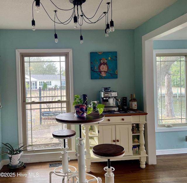 bar featuring a chandelier, baseboards, and wood finished floors