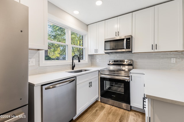 kitchen with white cabinets, stainless steel appliances, sink, and backsplash