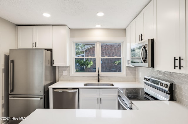 kitchen with appliances with stainless steel finishes, white cabinets, tasteful backsplash, and sink