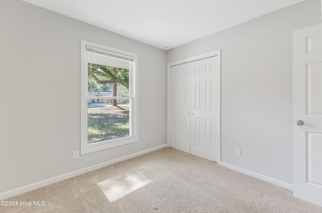 unfurnished bedroom with light carpet and a closet