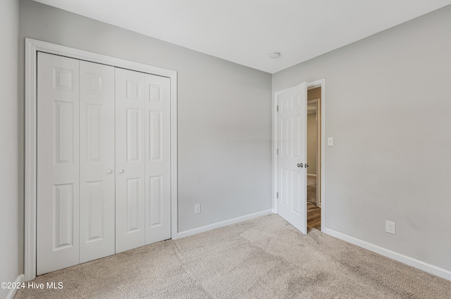 unfurnished bedroom with a closet and light colored carpet