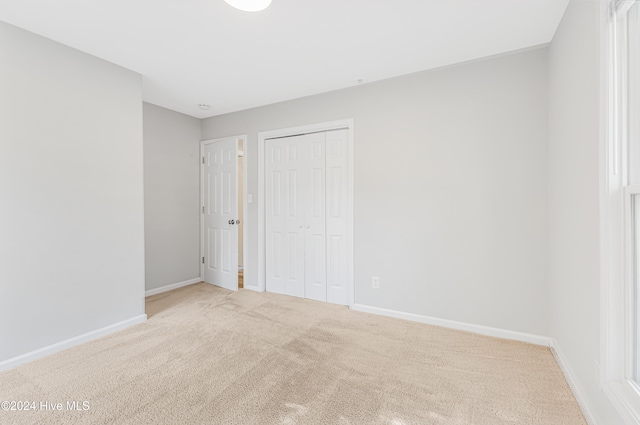 unfurnished bedroom with light carpet and a closet