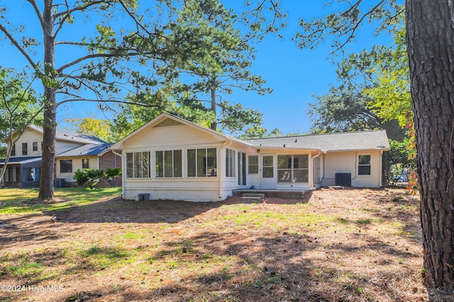 rear view of house with cooling unit, a lawn, and a sunroom