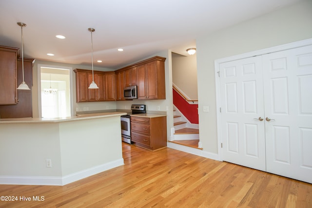 kitchen with kitchen peninsula, a chandelier, pendant lighting, light hardwood / wood-style floors, and stainless steel appliances