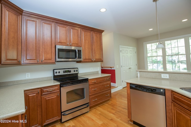 kitchen with stainless steel appliances, light hardwood / wood-style flooring, and hanging light fixtures