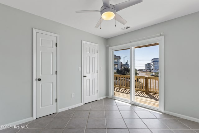 spare room featuring a ceiling fan, baseboards, and tile patterned floors