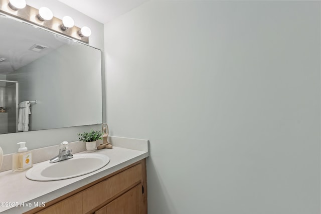 bathroom with visible vents, walk in shower, and vanity