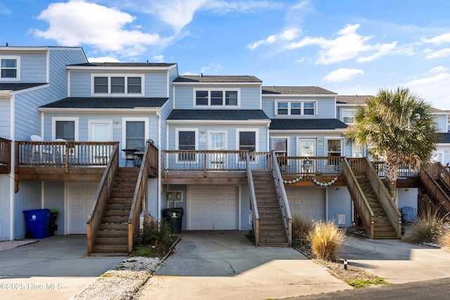 view of front of house with a shingled roof, concrete driveway, stairway, and an attached garage