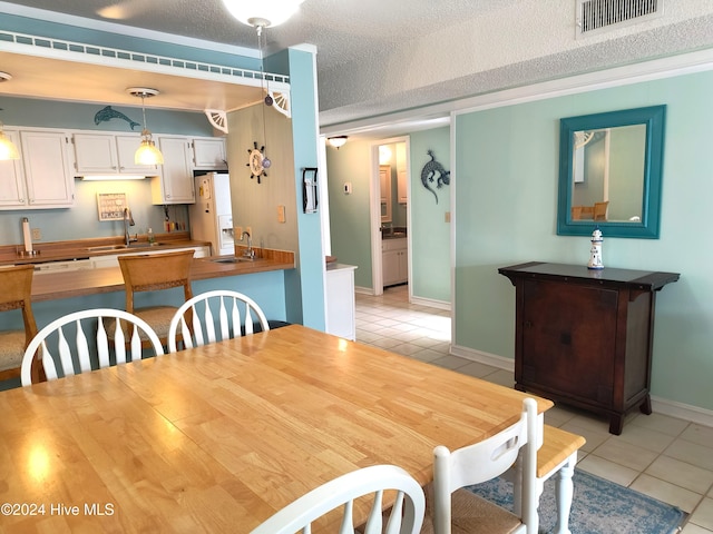 dining room with sink, a textured ceiling, and light tile patterned floors