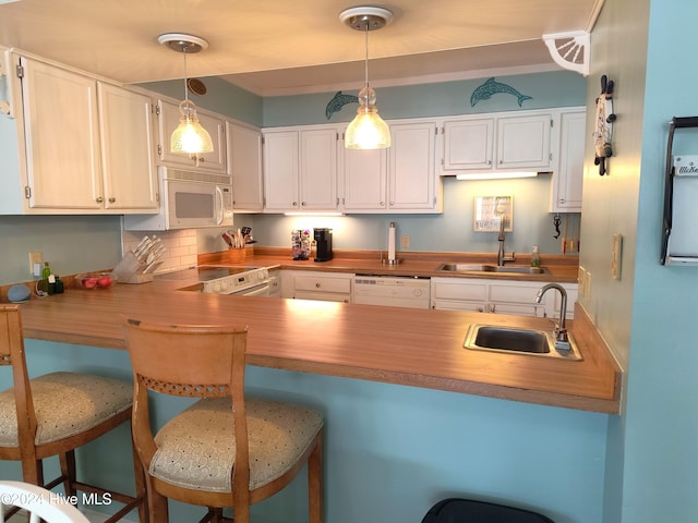 kitchen with sink, white cabinets, kitchen peninsula, and white appliances