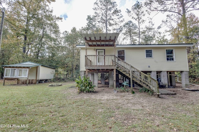 rear view of house featuring a wooden deck and a lawn