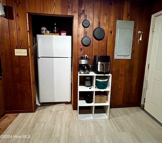 kitchen with electric panel, wood walls, and white refrigerator