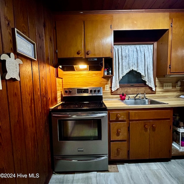 kitchen with stainless steel electric stove, decorative backsplash, sink, and light hardwood / wood-style floors