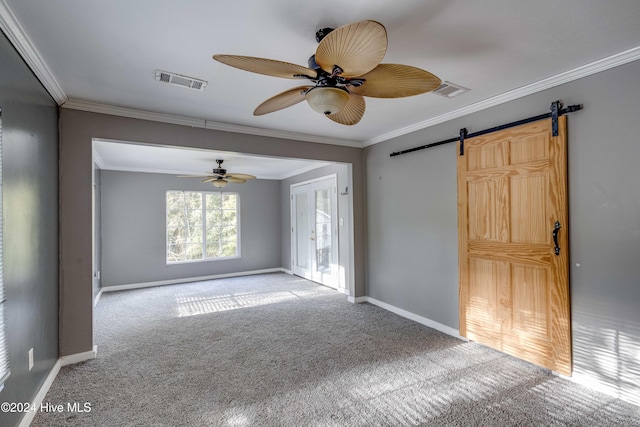 carpeted spare room featuring a barn door, ceiling fan, and ornamental molding