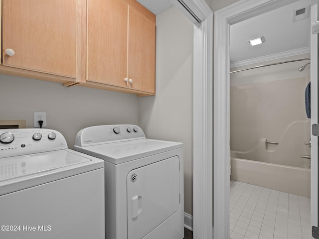 laundry area featuring cabinets, crown molding, tile patterned floors, and washer and clothes dryer