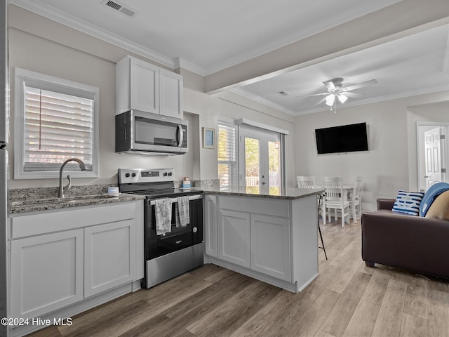 kitchen featuring ornamental molding, stainless steel appliances, light wood-type flooring, stone countertops, and white cabinets