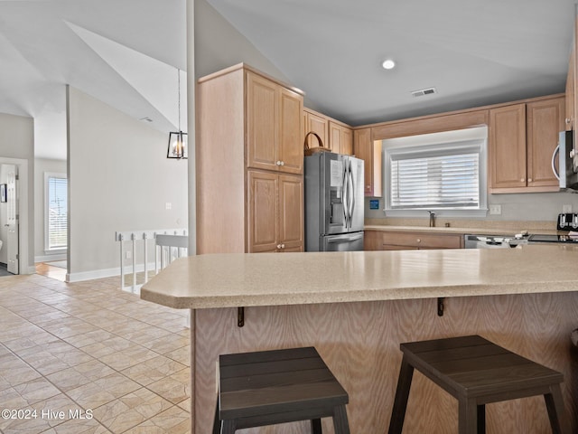 kitchen with a kitchen breakfast bar, appliances with stainless steel finishes, kitchen peninsula, and a wealth of natural light